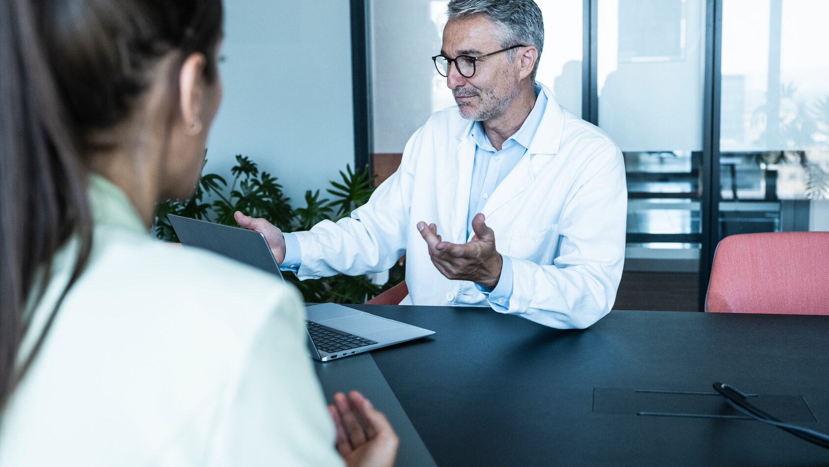 Ein männlicher Mediziner berät eine Patientin in einem Büro.