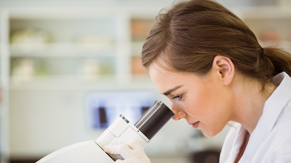 Symbolbild Krebsforschung , eine Frau schaut in ein Mikroskop